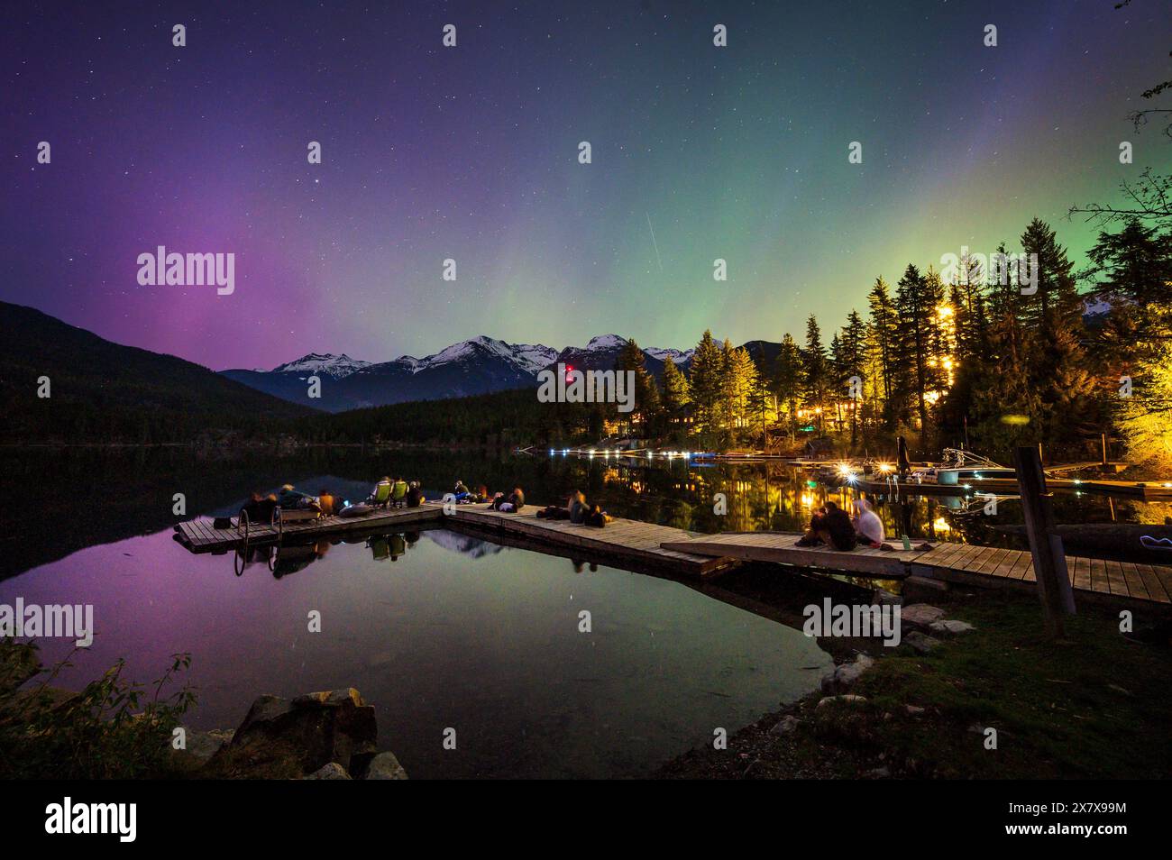 Crowds of people watch the Northern Lights shine brightly over Green Lake, near Whistler BC, Canada.  A solar storm that evening caused an unusually b Stock Photo