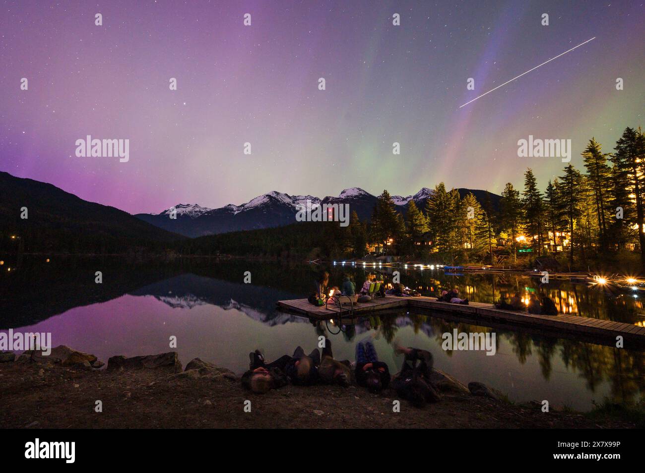 Crowds of people watch the Northern Lights shine brightly over Green Lake, near Whistler BC, Canada.  A solar storm that evening caused an unusually b Stock Photo