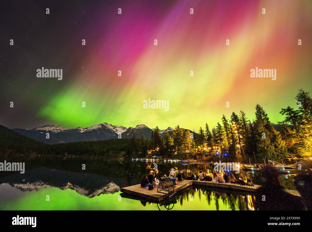 Crowds of people watch the Northern Lights shine brightly over Green Lake, near Whistler BC, Canada.  A solar storm that evening caused an unusually b Stock Photo