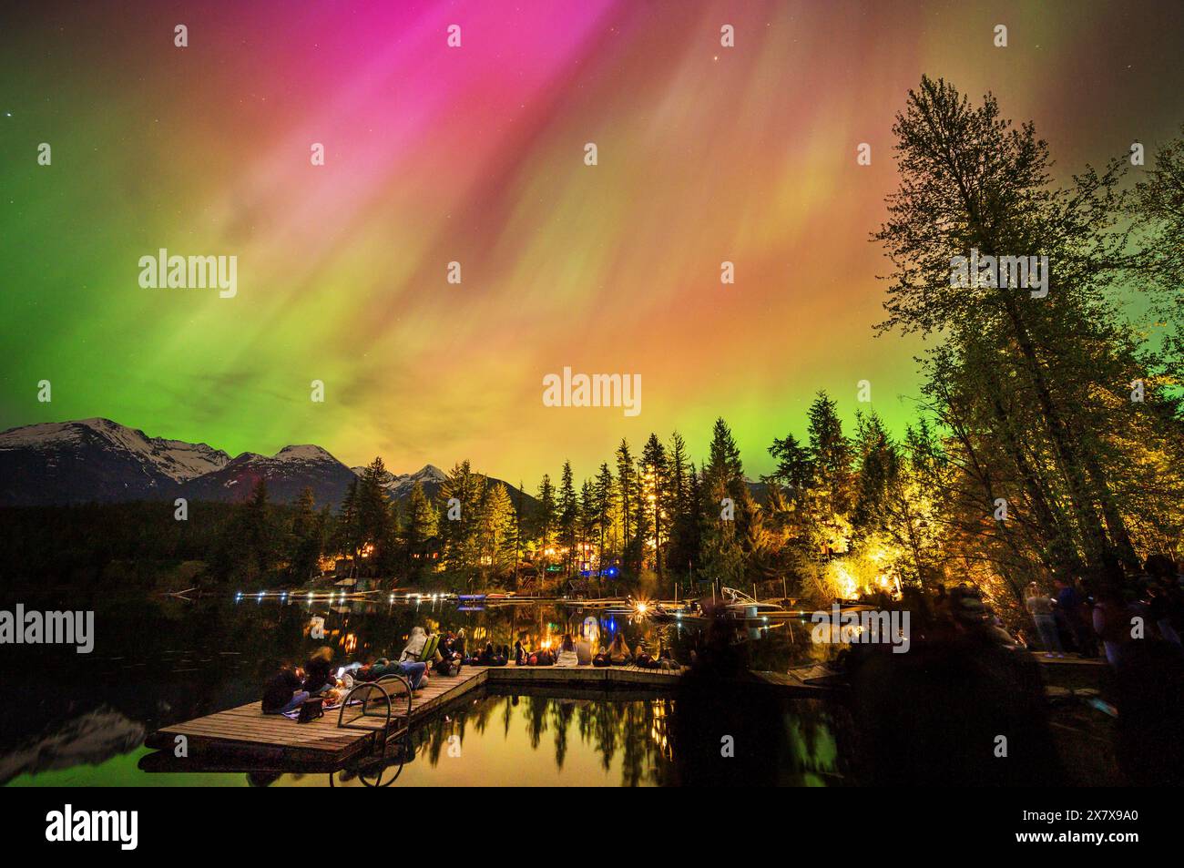 Crowds of people watch the Northern Lights shine brightly over Green Lake, near Whistler BC, Canada.  A solar storm that evening caused an unusually b Stock Photo
