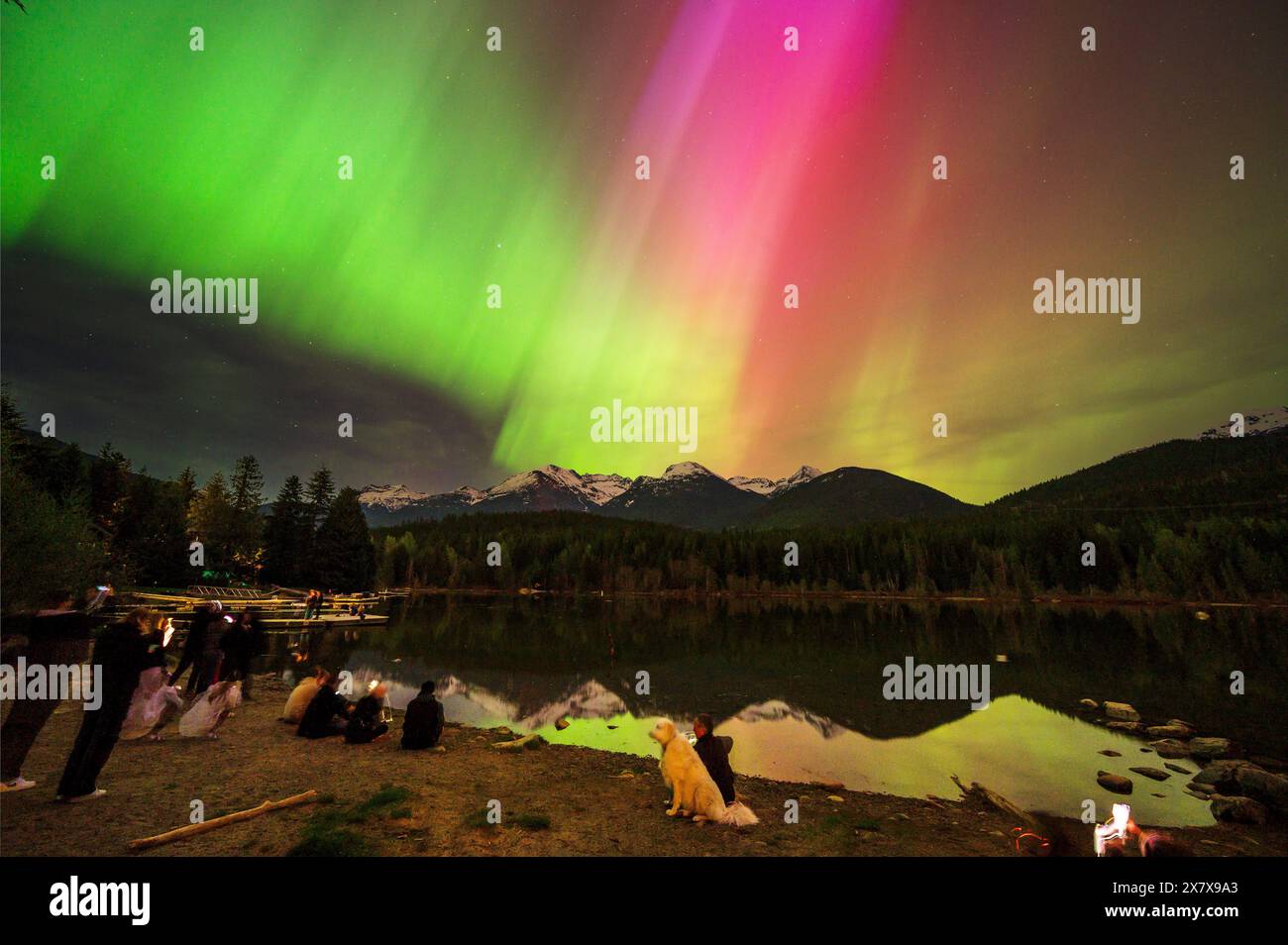 Crowds of people watch the Northern Lights shine brightly over Green Lake, near Whistler BC, Canada.  A solar storm that evening caused an unusually b Stock Photo