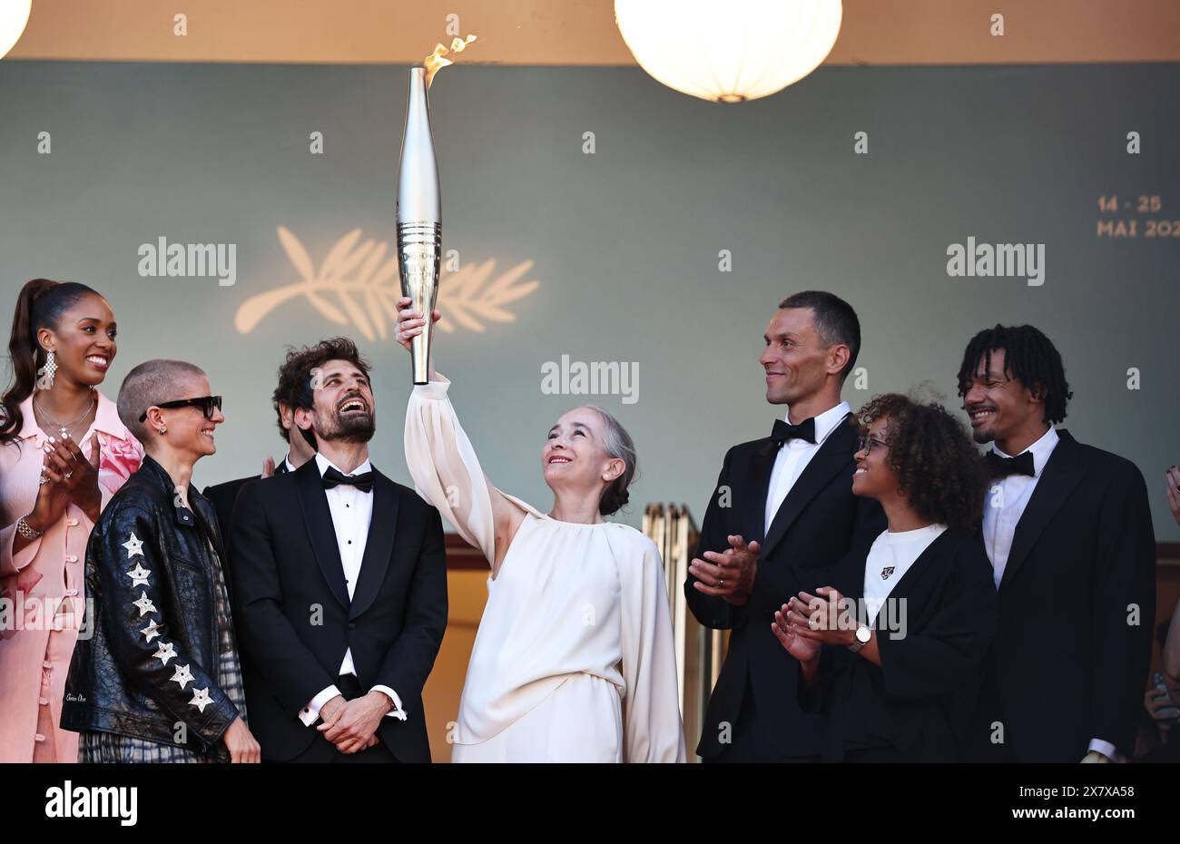 Cannes. 21st May, 2024. Delphine Ernotte (2nd R), head of France Televisions, holds up the Paris 2024 Olympic torch at the 77th edition of the Cannes Film Festival in Cannes, southern France, on May 21, 2024, as part of the Olympics torch relay. Credit: Gao Jing/Xinhua/Alamy Live News Stock Photo