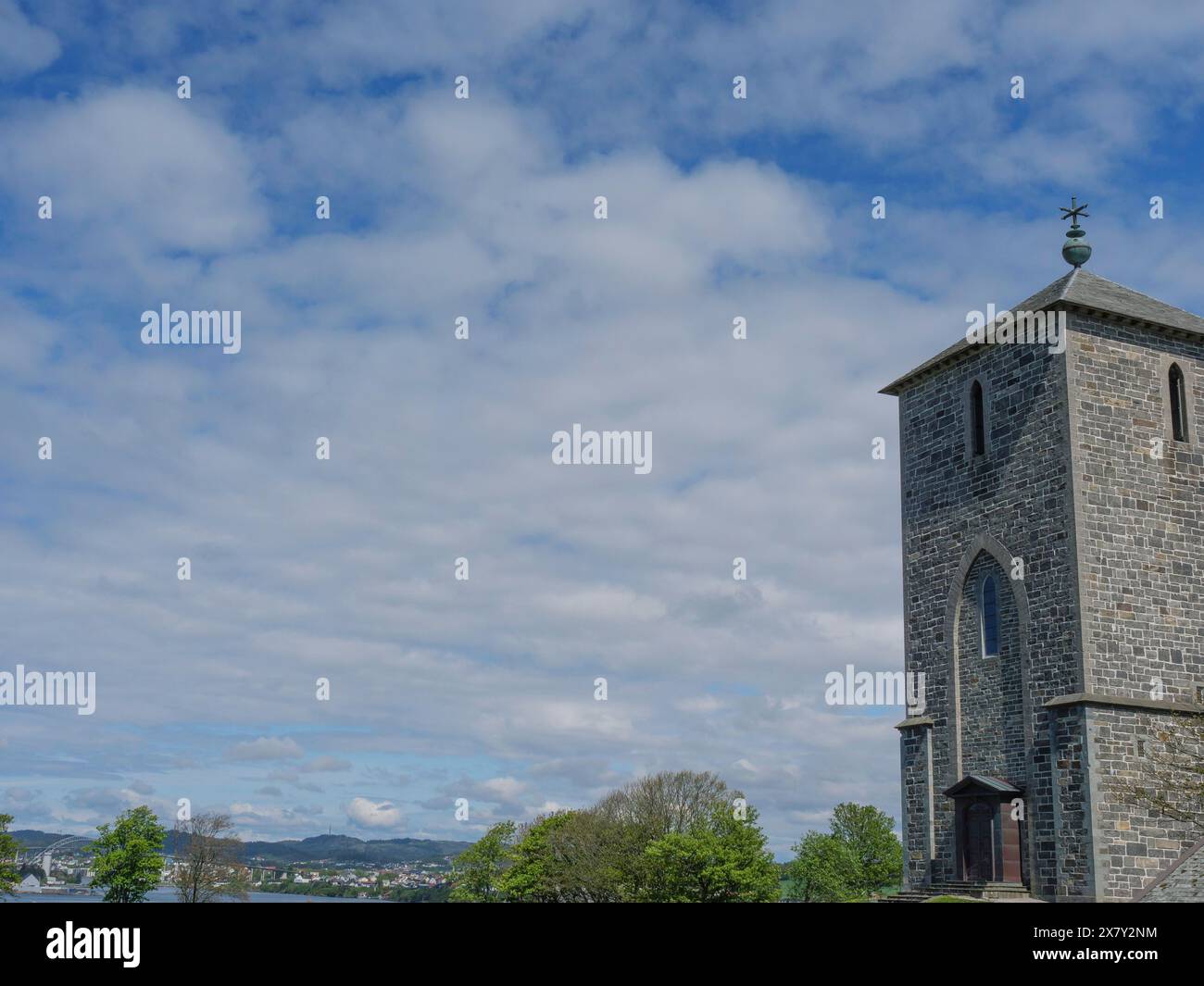High stone church tower surrounded by nature with a cloudy sky in the ...