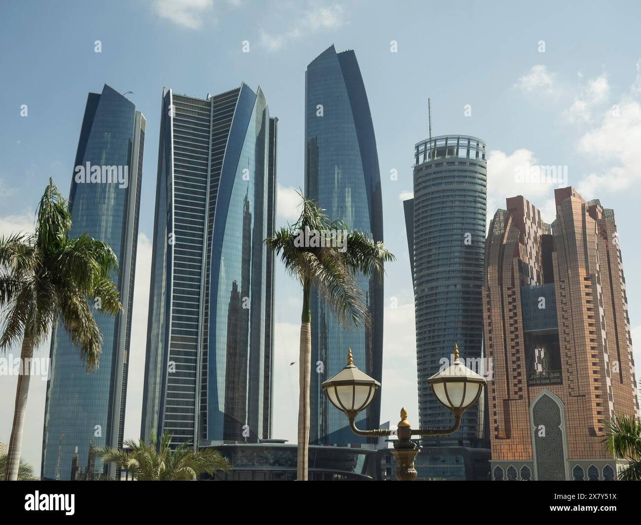 Modern skyscrapers and palm trees, with decorative lanterns in the foreground, under blue sky, modern skyscrapers with palms in the foreground, skylin Stock Photo