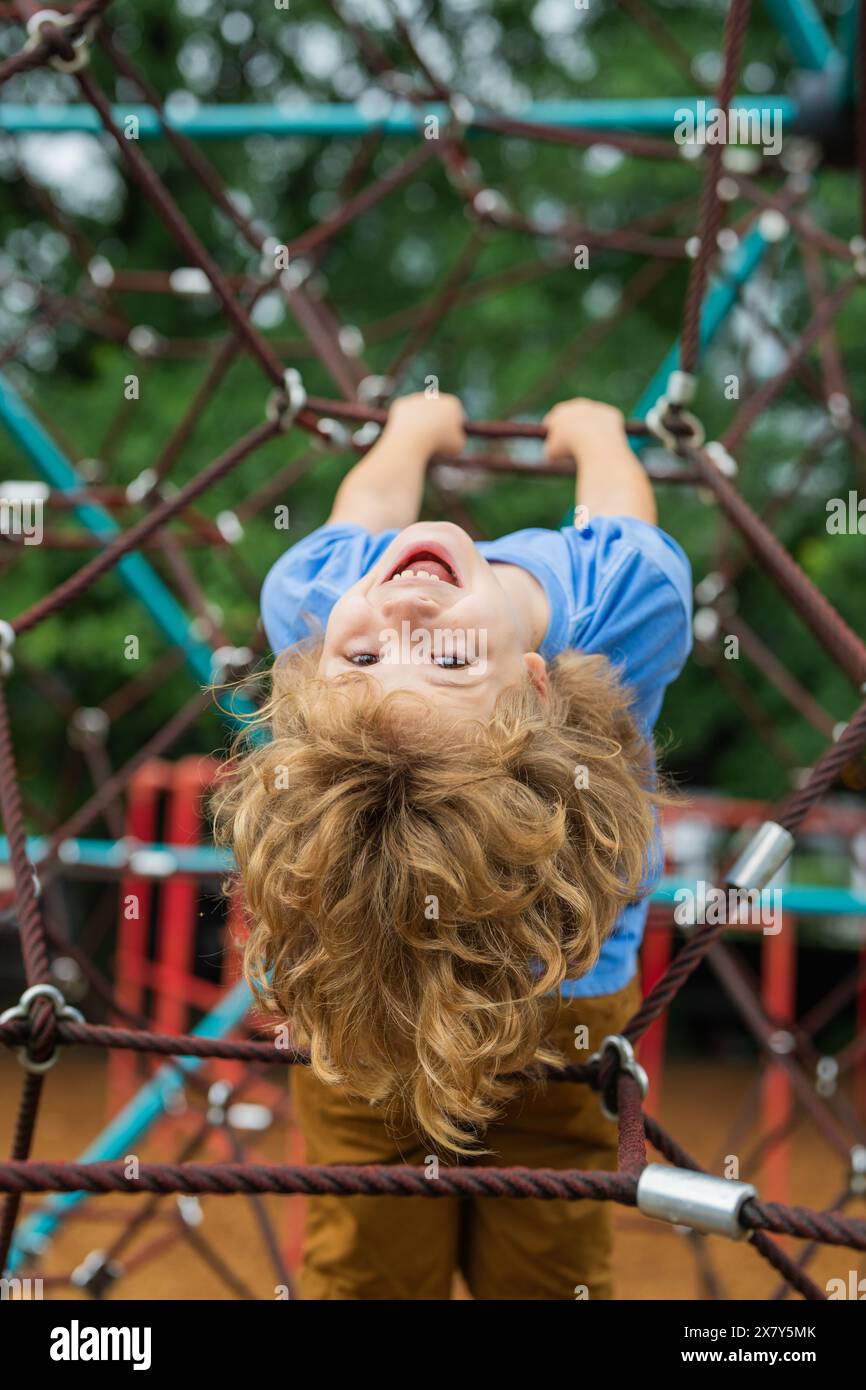 The child is hanging upside down on the playground equipment. The ...