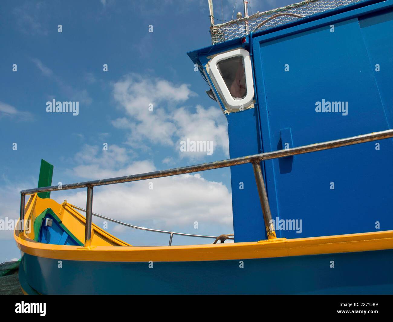 Close-up of a blue and yellow boat with clear sky and few clouds in the ...