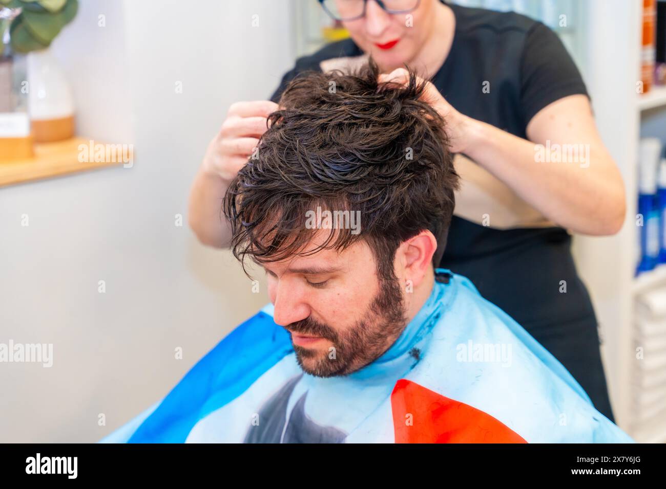 Hairstylist attaching a new capillary prosthesis to a man's head ...