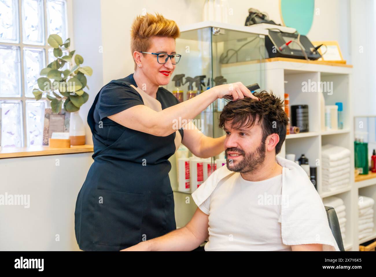 Hairdresser attaching a capillary prosthesis to a happy bald man in the ...