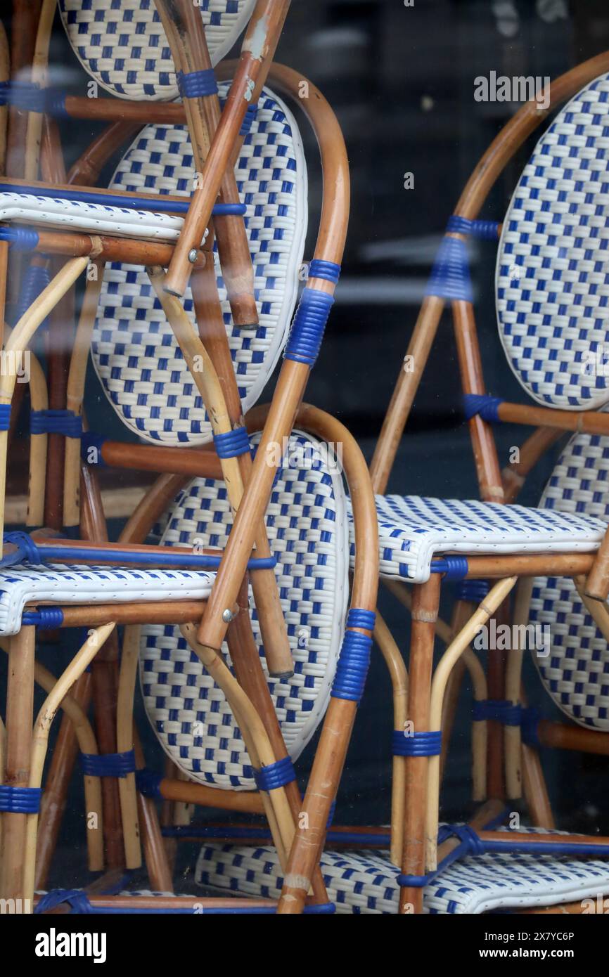 Chairs stacked on top of each other in the window of a closed restaurant Stock Photo