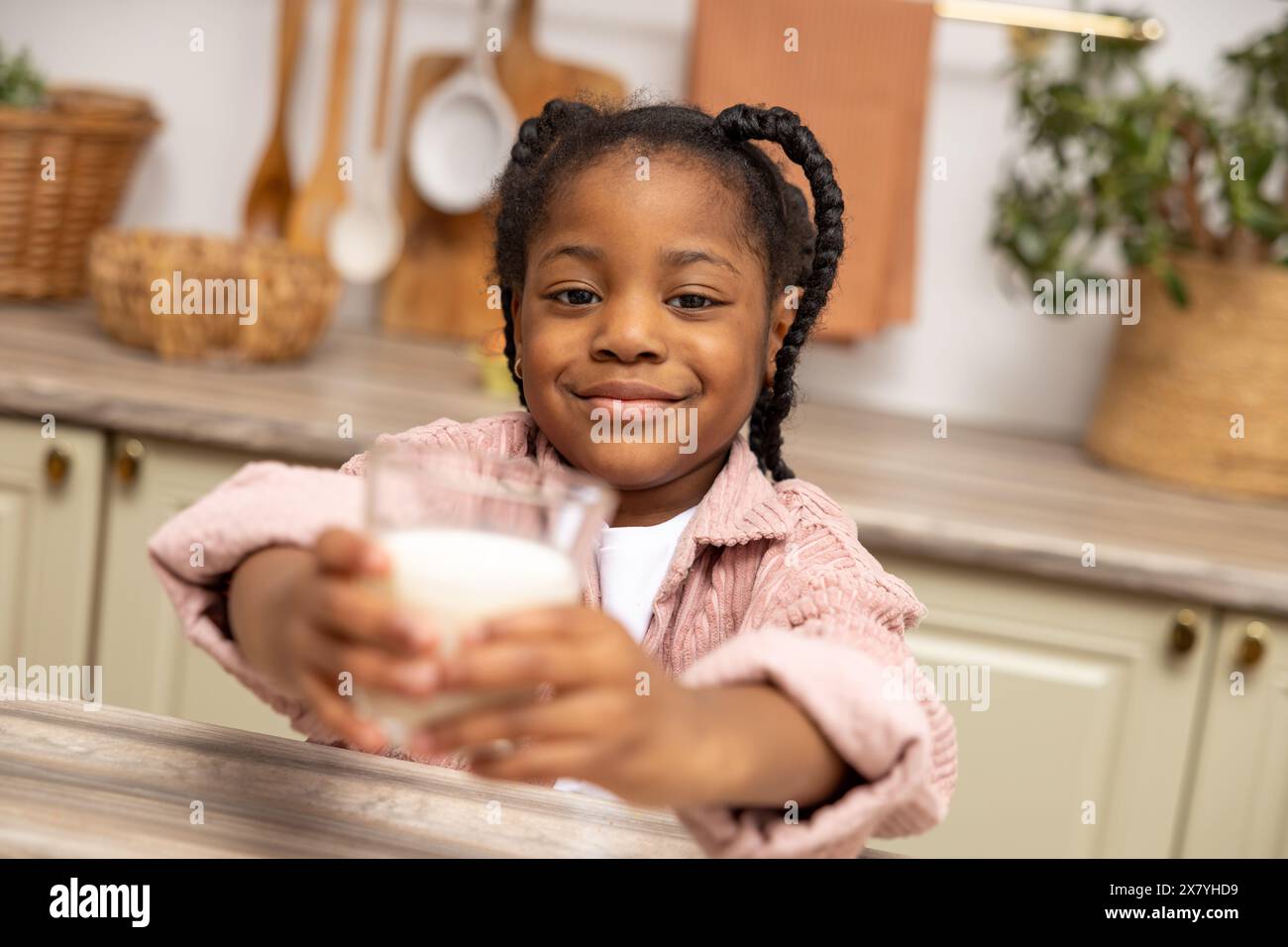 Happy African American kid drinking milk in kitchen Stock Photo