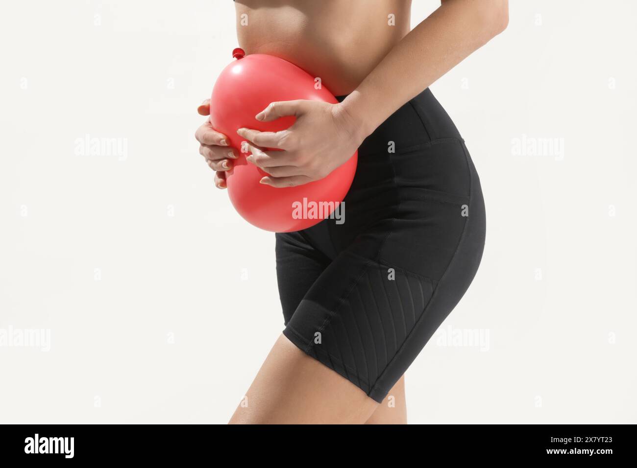 Young woman holding balloon as a sign of an stomach inflation, bloating and menstrual cramps concept Stock Photo