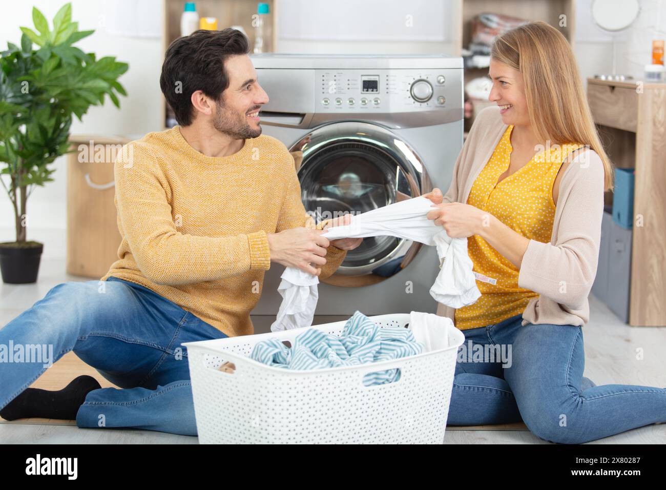 happy couple having fun doing laundry together Stock Photo
