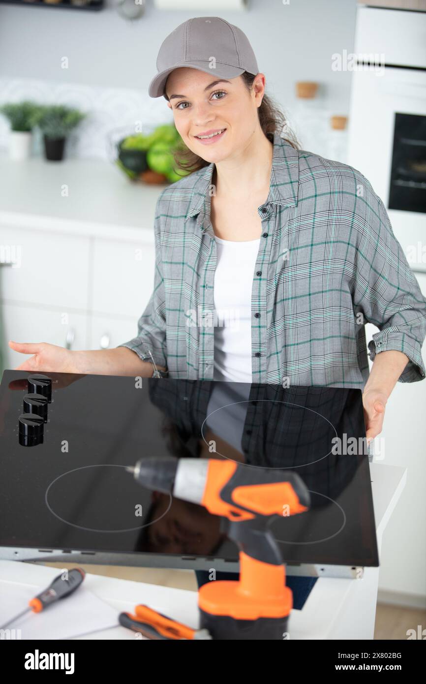 woman technician installing hob in clients kitchen Stock Photo