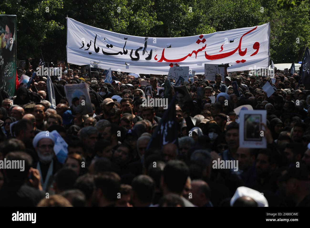 Tehran, Iran. May 22, 2024, Tehran, Iran: Iranian mourners hold up a huge placard written, ''and a martyr was the vote of our nation'' during a funeral ceremony for the late President Ebrahim Raisi and his companions who were killed during a helicopter crash in a mountainous region of the country's northwest, in Tehran. Credit: ZUMA Press, Inc./Alamy Live News Stock Photo