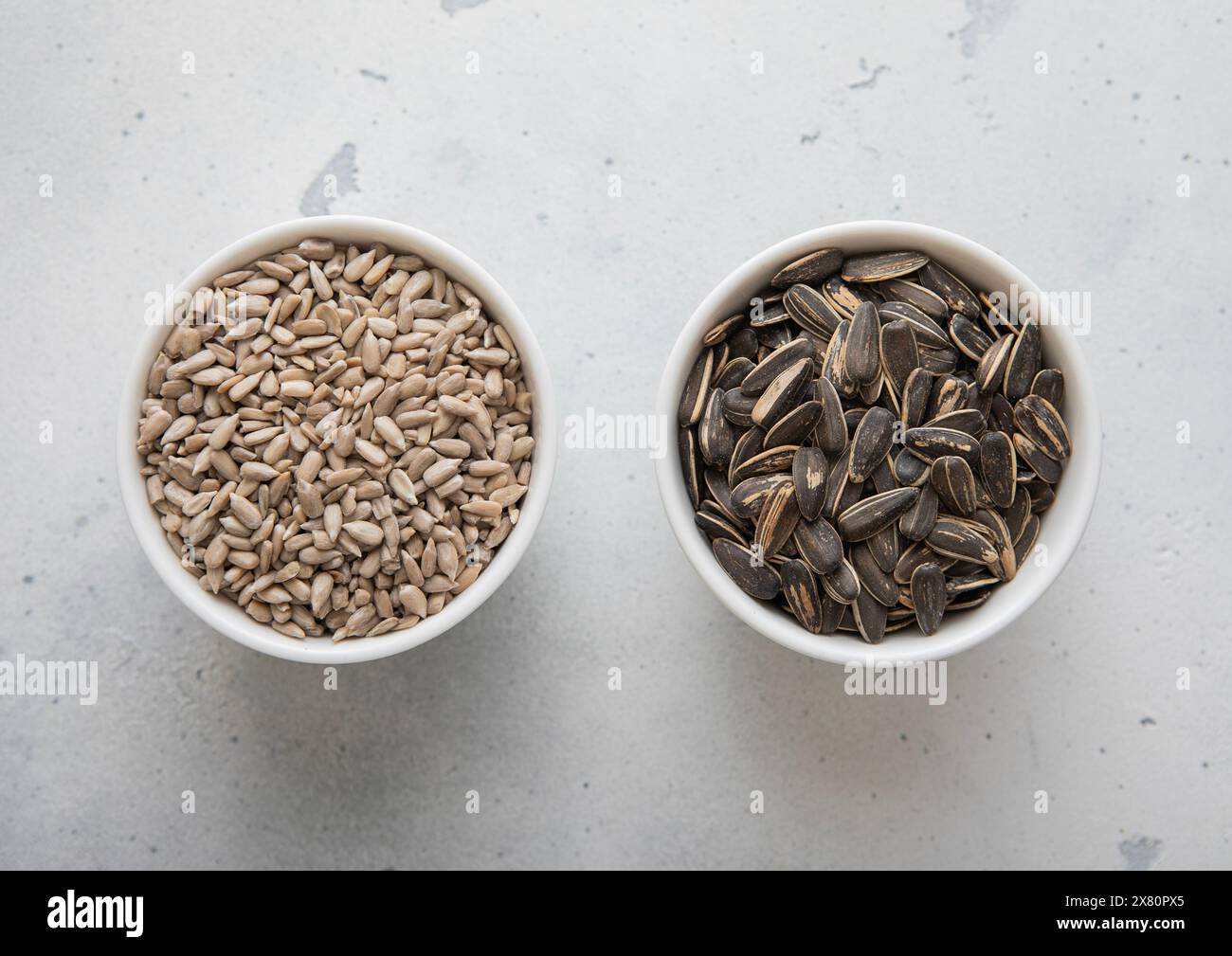 Whole and peeled healthy sunflower seeds in ceramic bowl plates on ...
