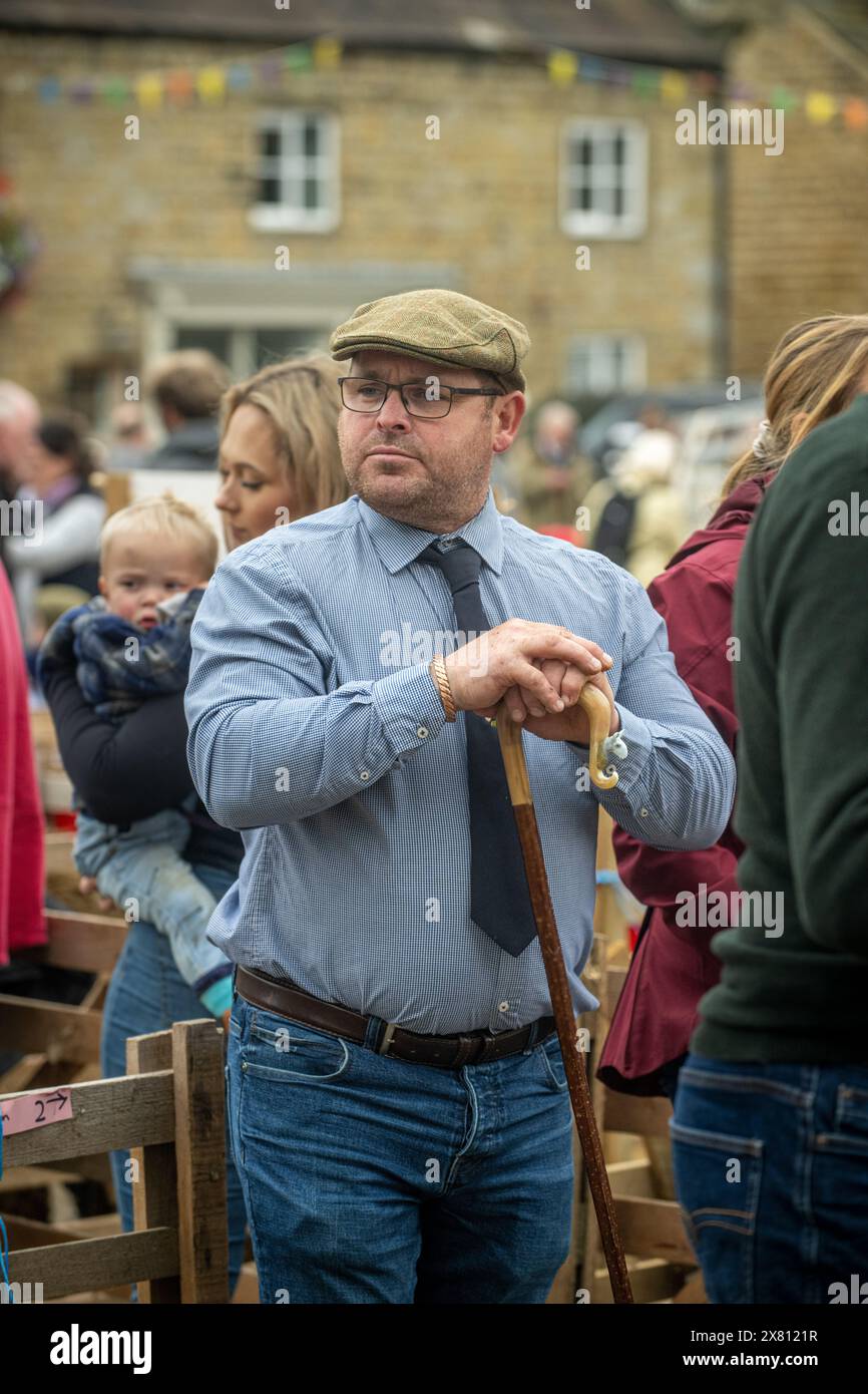 Male judge wearing a flat cap, shirt, and tie, resting on his shepherd's crook as he pauses a moment from judging at the Masham Sheep Fair, UK Stock Photo