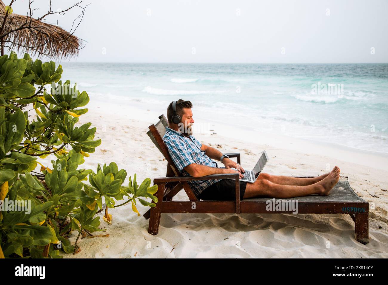 man working on laptop on exotic beach Stock Photo