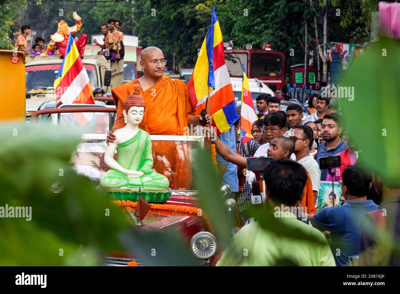 A Buddhist monk rides in an open vehicle with a statue of Lord Buddha ...