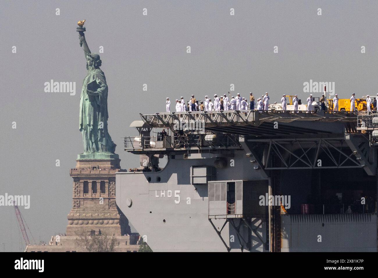 U.S. Sailors and Marines stand on the deck of the USS Bataan as it ...