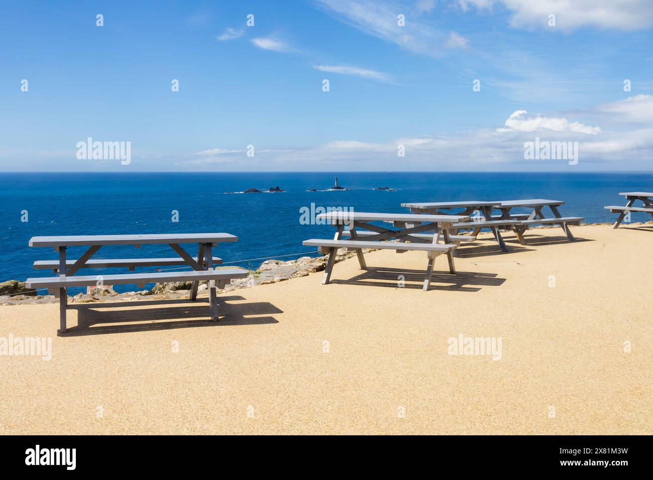 Empty trestle picnic tables at Lands End. The Longships lighthouse is behind. Cornwall, West Country, England Stock Photo