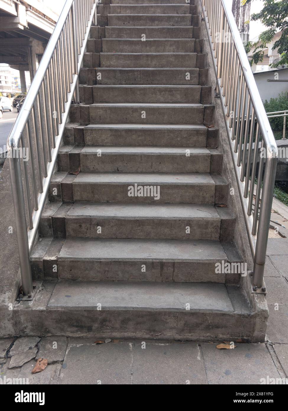The concrete staircase of the overpass bridge near the junction in the city, stainless steel railing along the way, front view with the copy space. Stock Photo
