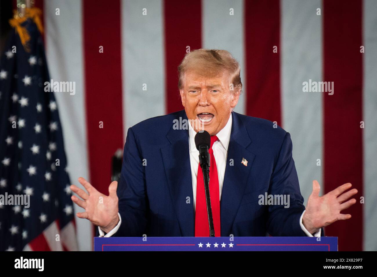Donald Trump speaks on stage and uses hand gestures at a campaign rally ...