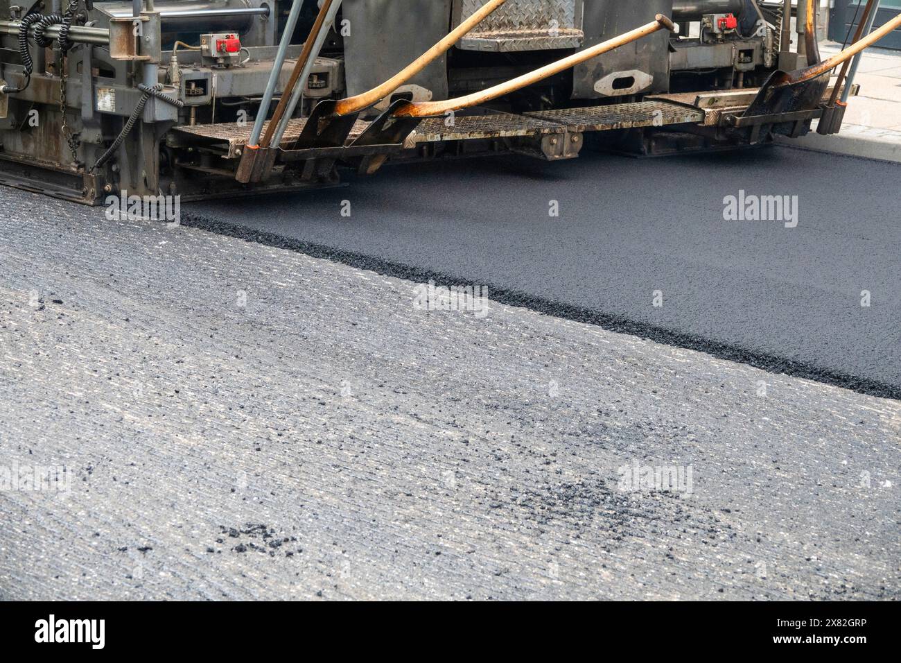 Repair of asphalt road surface - old layer removed and a coating Industrial pavement truck laying new fresh asphalt on construction site. Stock Photo