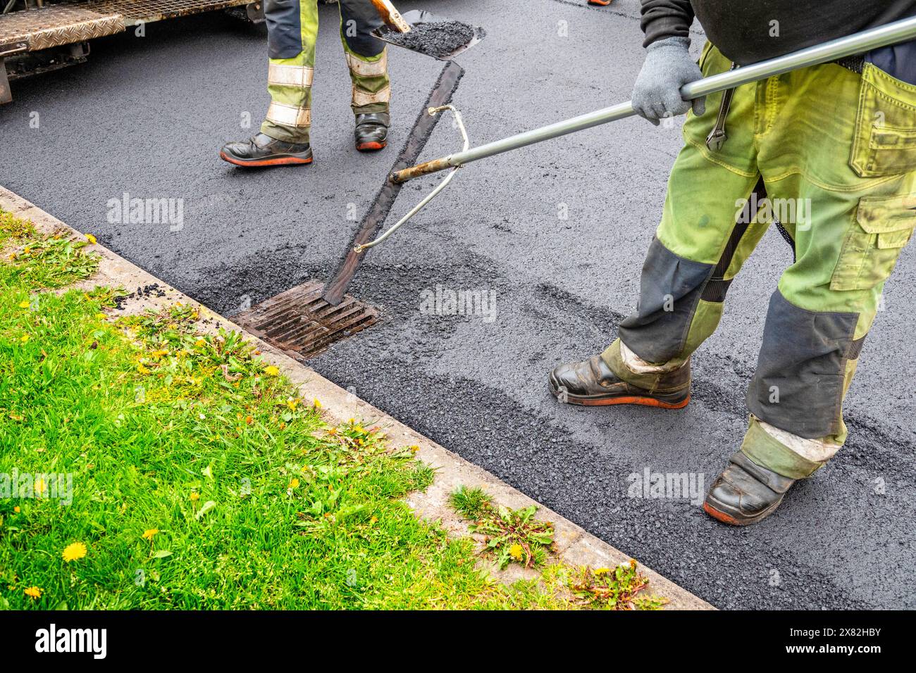 Men at work at asphalting, urban road under construction. Stock Photo