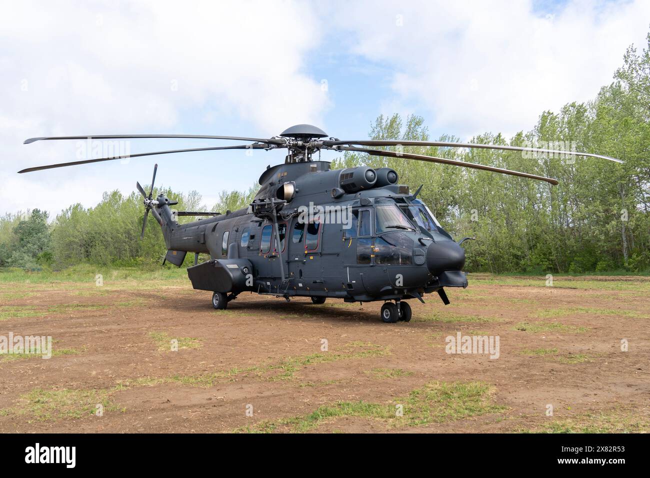 Black painted modern H225M military transport helicopter stationary on the ground Stock Photo