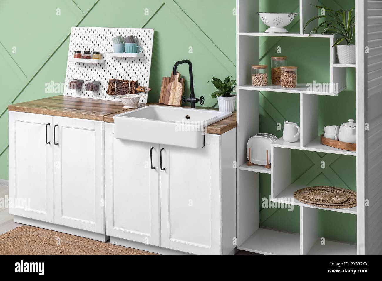 Pegboard, white counters and rack near green wall in interior of modern ...