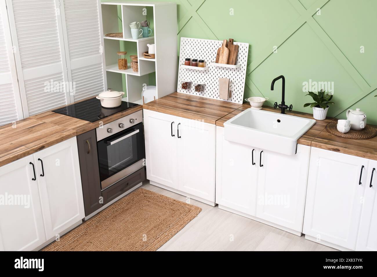 Interior of stylish kitchen with white counters, pegboard and green ...
