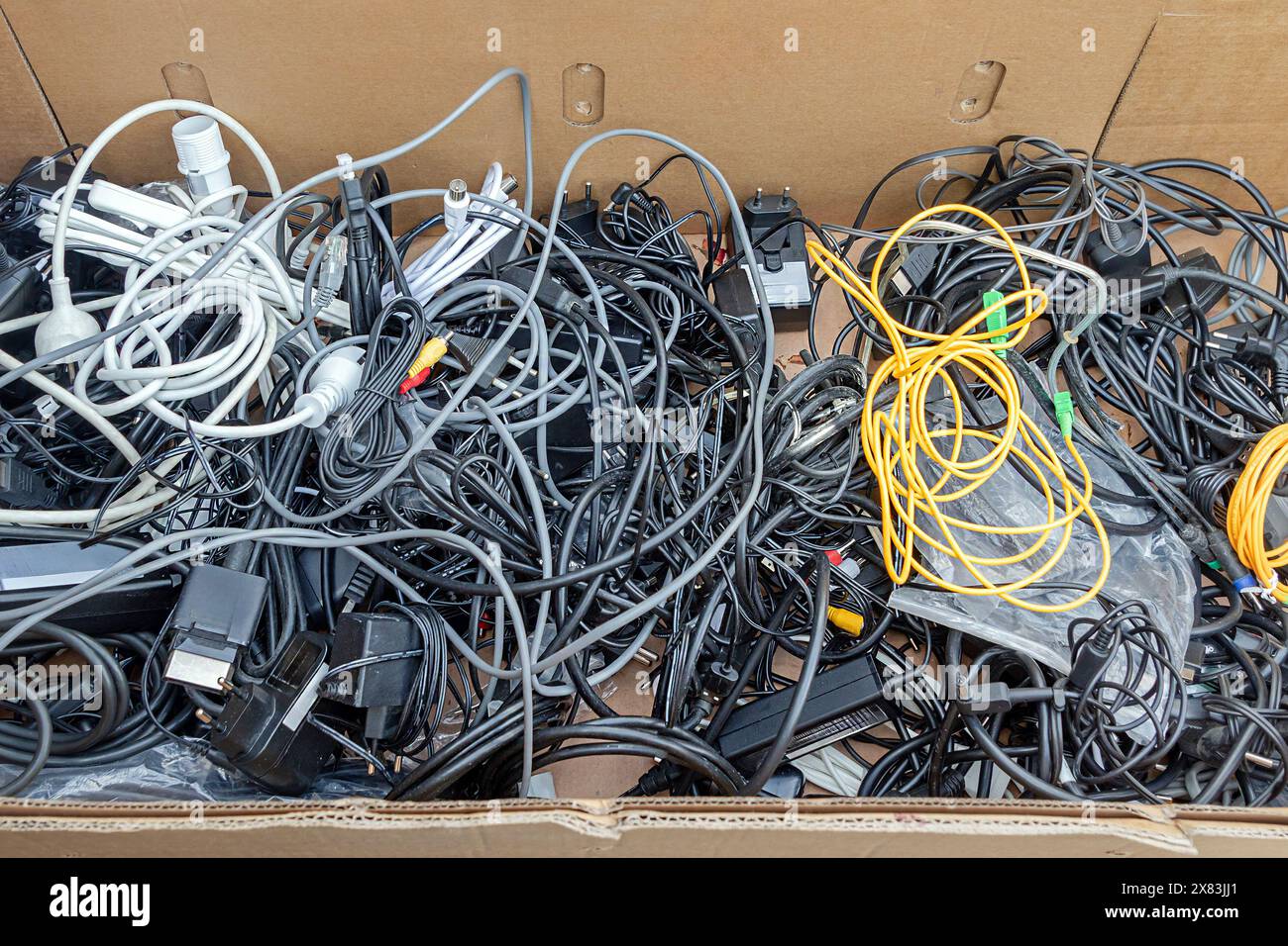 Pile of chargers with tied cables inside cardboard box Stock Photo