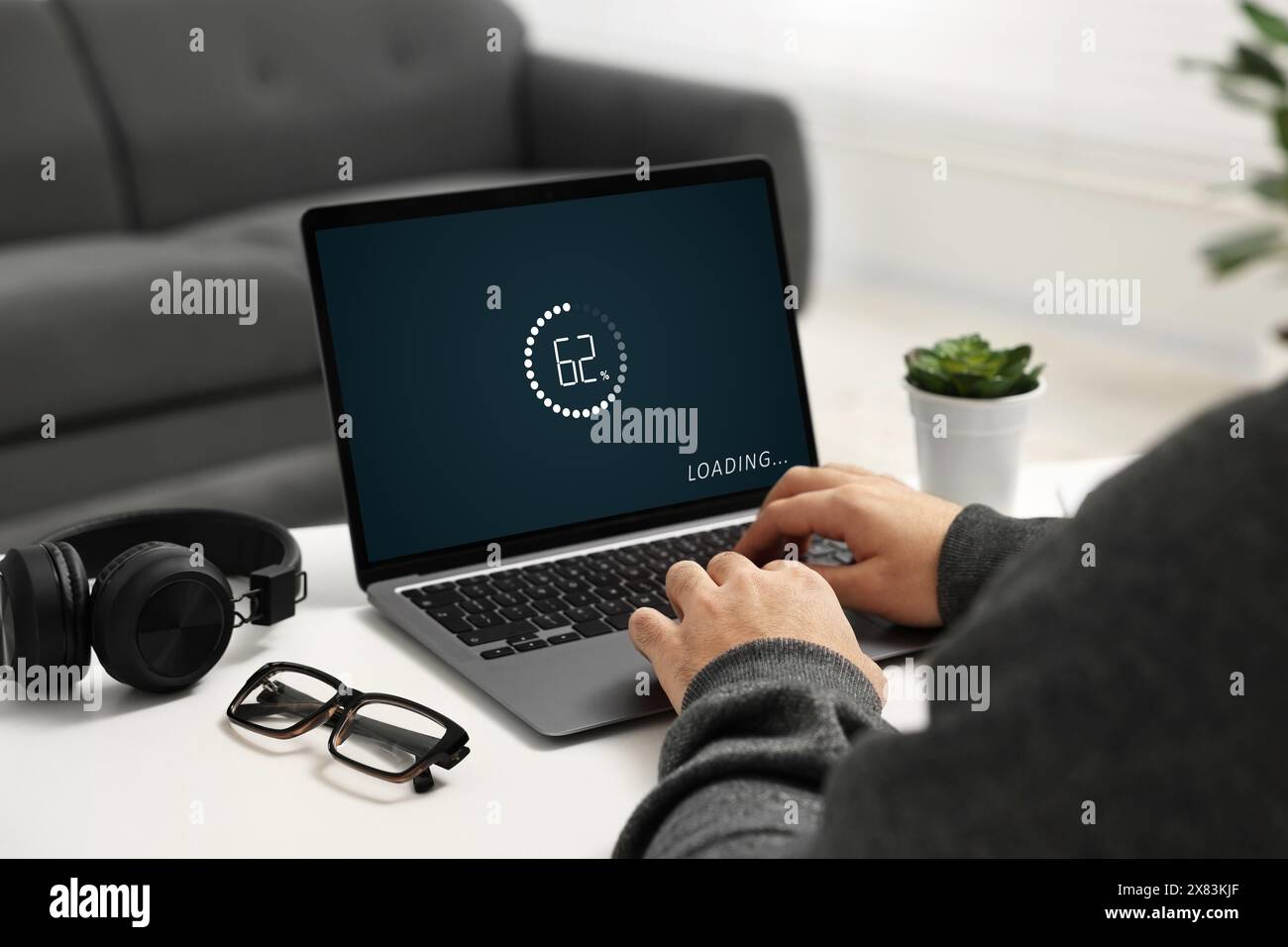 Loading screen displaying progress. Man working on laptop at table indoors, closeup Stock Photo