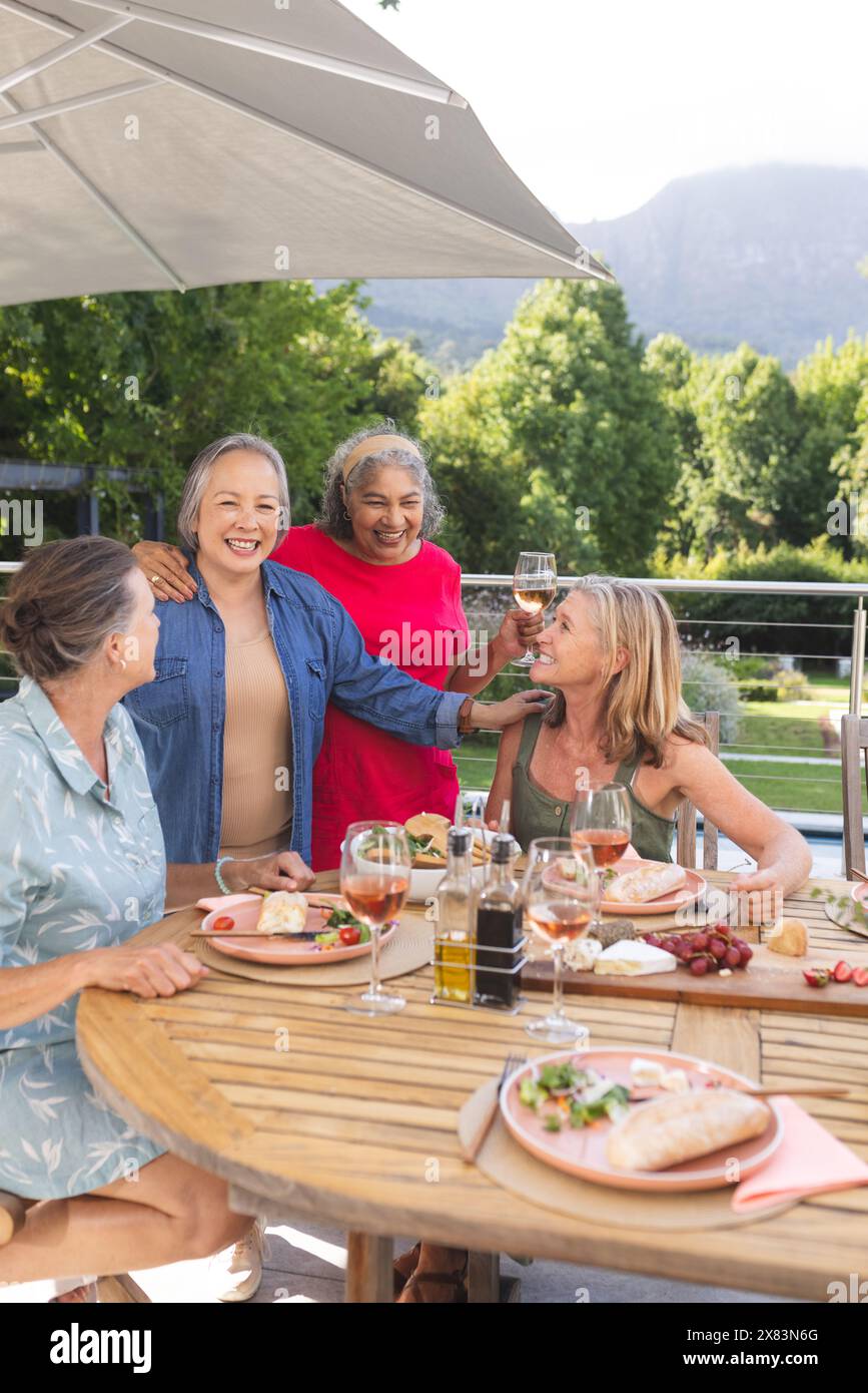 Diverse senior female friends laughing over meal outdoors Stock Photo