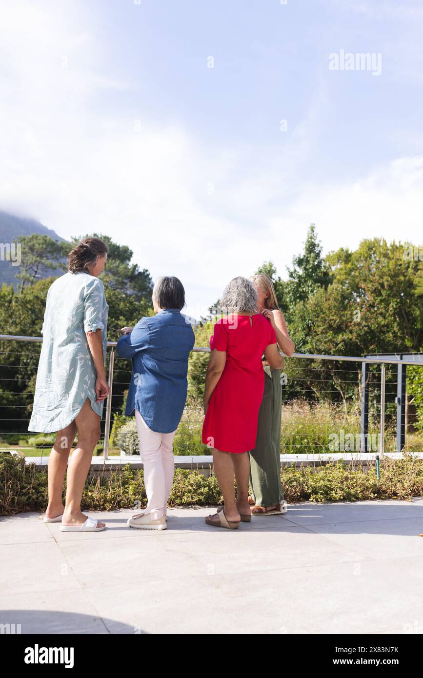 Diverse senior female friends standing together outdoors, looking out Stock Photo