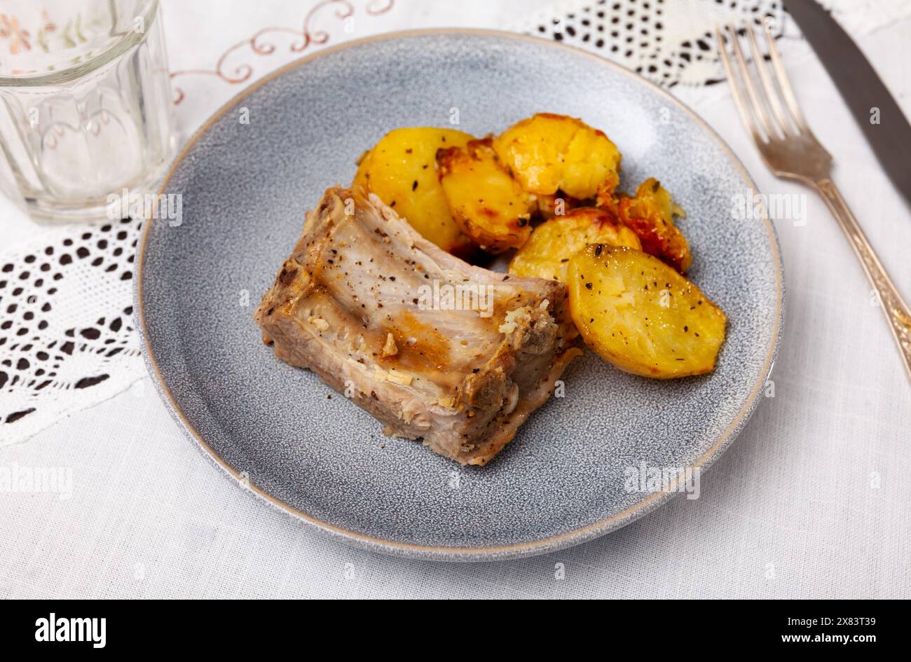 Pork ribs with boiled potatoes and spices on ceramic plate Stock Photo