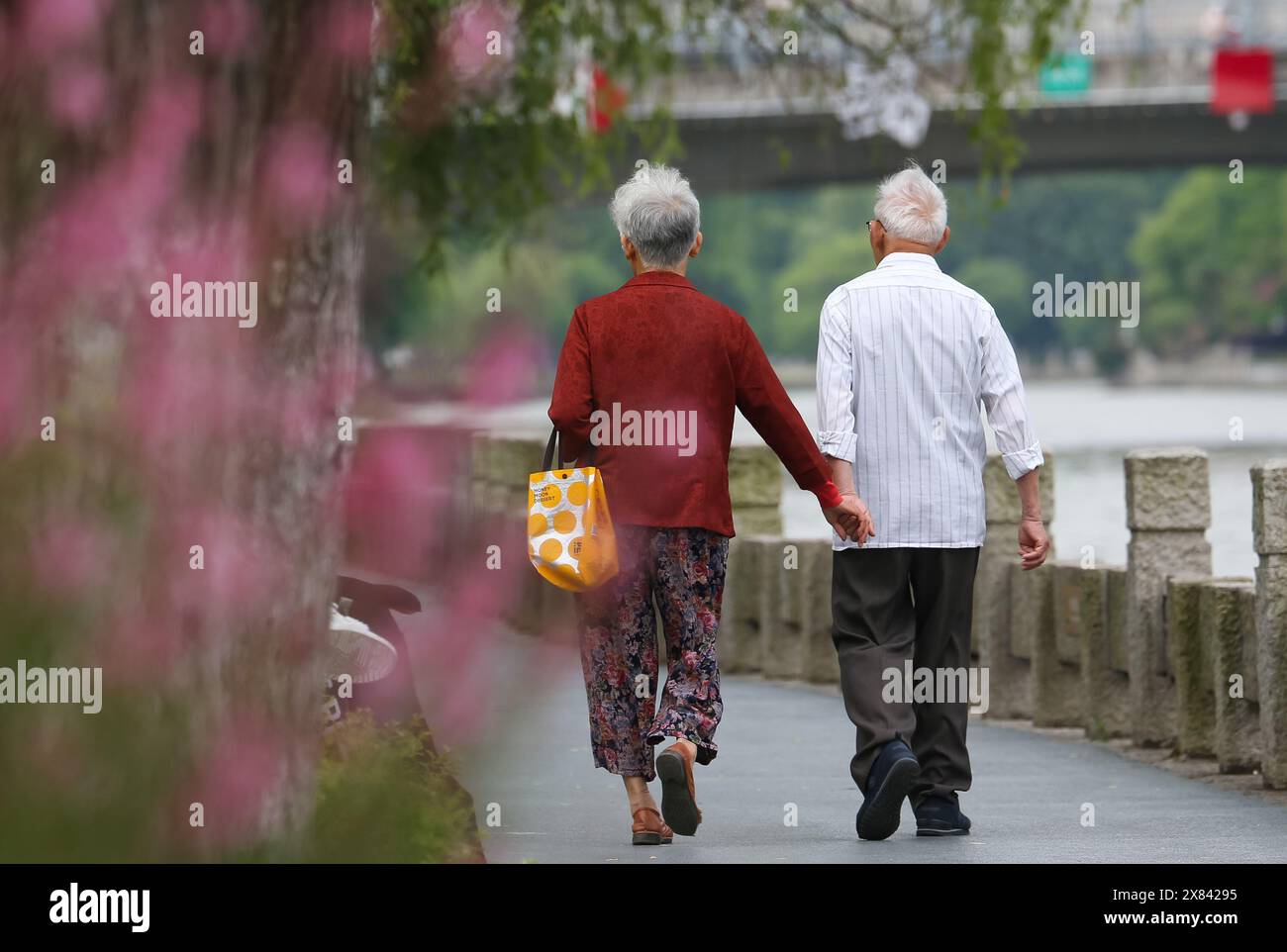 Wuxi, China's Jiangsu Province. 22nd May, 2024. People take a walk at a scenic belt along the Liangxi River in Wuxi, east China's Jiangsu Province, May 22, 2024. Wuxi city is building a scenic belt along the Liangxi River in recent years to provide its local people with leisure space. Credit: Zhong Xueman/Xinhua/Alamy Live News Stock Photo