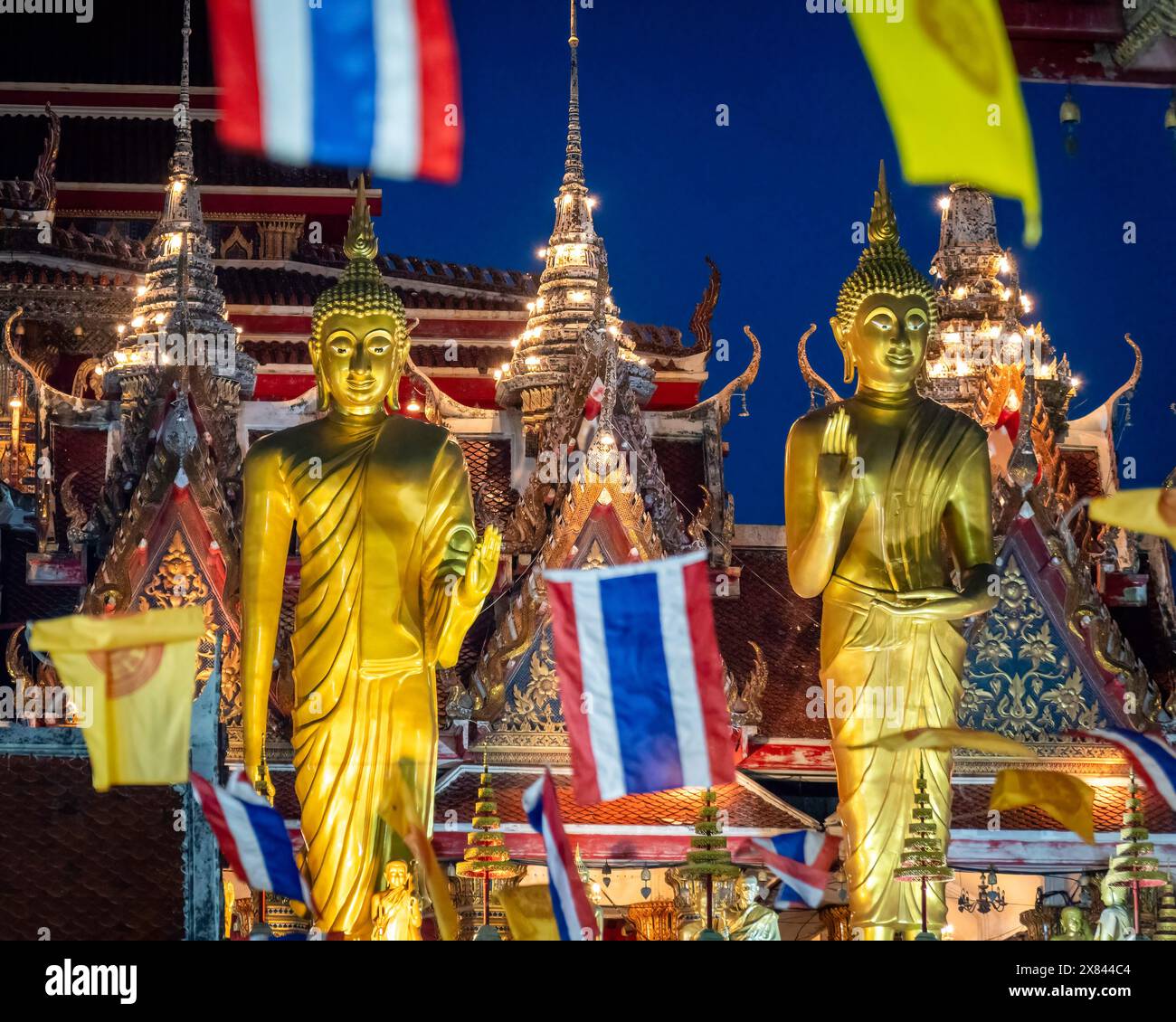 May 22, 2024, Bangkok, Thailand: A view of two Buddhist statues with the Thai flag and the yellow Thai monarchy flag, at Lat Phrao Temple, situated in a low-income community in Bangkok, Thailand. Visakha Bucha, one of Thailand's most important Buddhist holidays, commemorates the birth, enlightenment, and passing of Gautama Buddha, all on the same date. Thai Buddhists typically visit temples to make merit, which involves activities such as giving alms to monks, listening to sermons, and participating in various religious rituals. (Credit Image: © Nathalie Jamois/SOPA Images via ZUMA Press Wire) Stock Photo