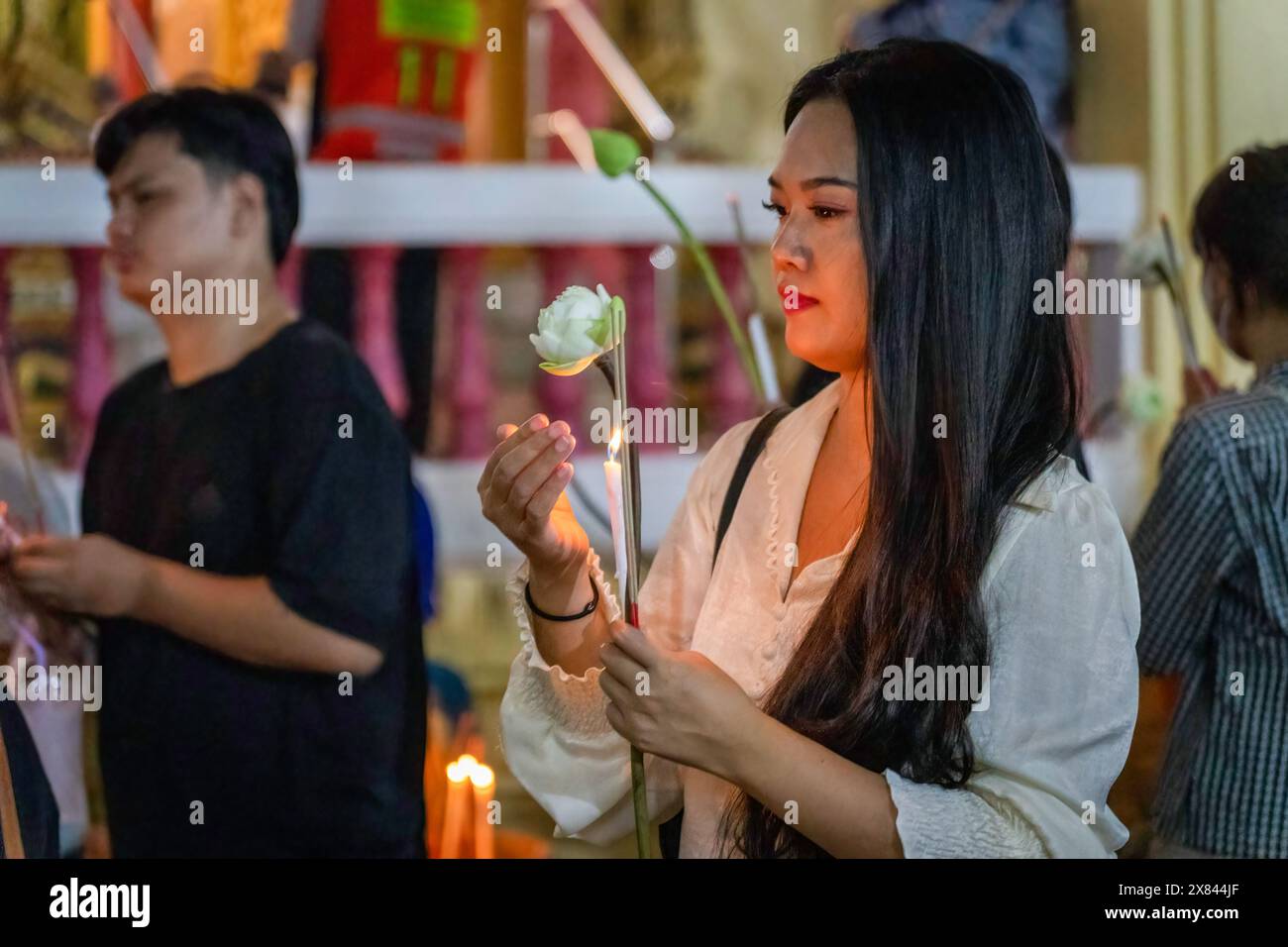 May 22, 2024, Bangkok, Thailand: A Thai woman is seen holding a candle and a lotus flower, on Visakha Bucha day, at Lat Phrao Temple, situated in a low-income community, in Bangkok, Thailand. Visakha Bucha, one of Thailand's most important Buddhist holidays, commemorates the birth, enlightenment, and passing of Gautama Buddha, all on the same date. Thai Buddhists typically visit temples to make merit, which involves activities such as giving alms to monks, listening to sermons, and participating in various religious rituals. (Credit Image: © Nathalie Jamois/SOPA Images via ZUMA Press Wire) EDI Stock Photo