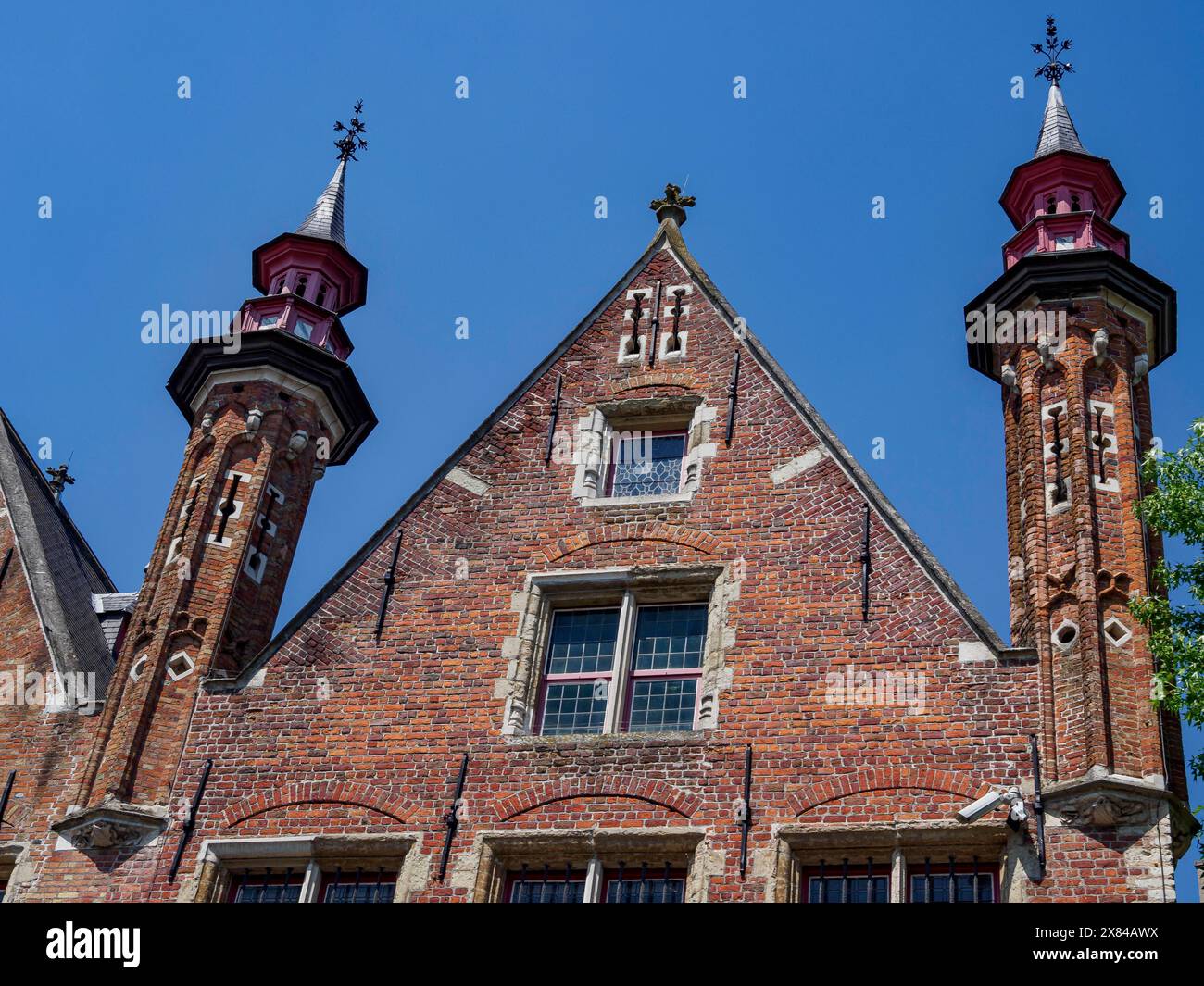 Facade of an old building with striking gothic towers and green shutters under a clear sky, old historic house facades with towers and bridges by a Stock Photo