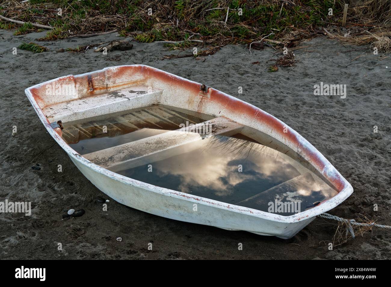 A neglected little dingy sits on the sand waiting to be bailed out A neglected little dingy sits on the sand waiting to be bailed out