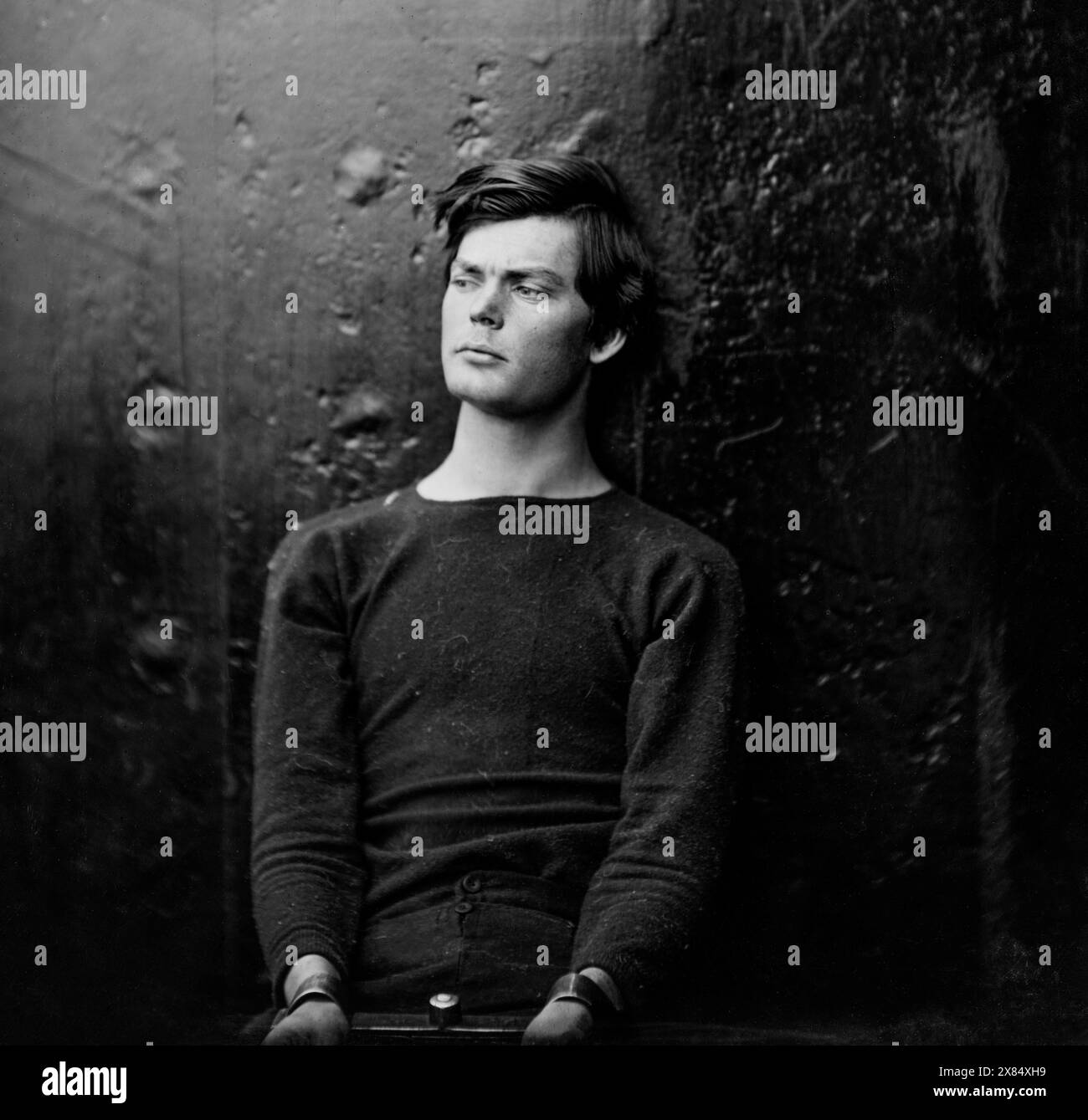 Lewis Powell (aka Lewis Payne), in sweater, seated and manacled, one of the conspirators in the Abraham Lincoln assassination. This photograph has background of dark metal, and was presumably taken on U.S.S. Saugus, where he was for a time confined. Washington Navy Yard, District of Columbia. 27 April 1865. By Alexander Gardner. Stock Photo