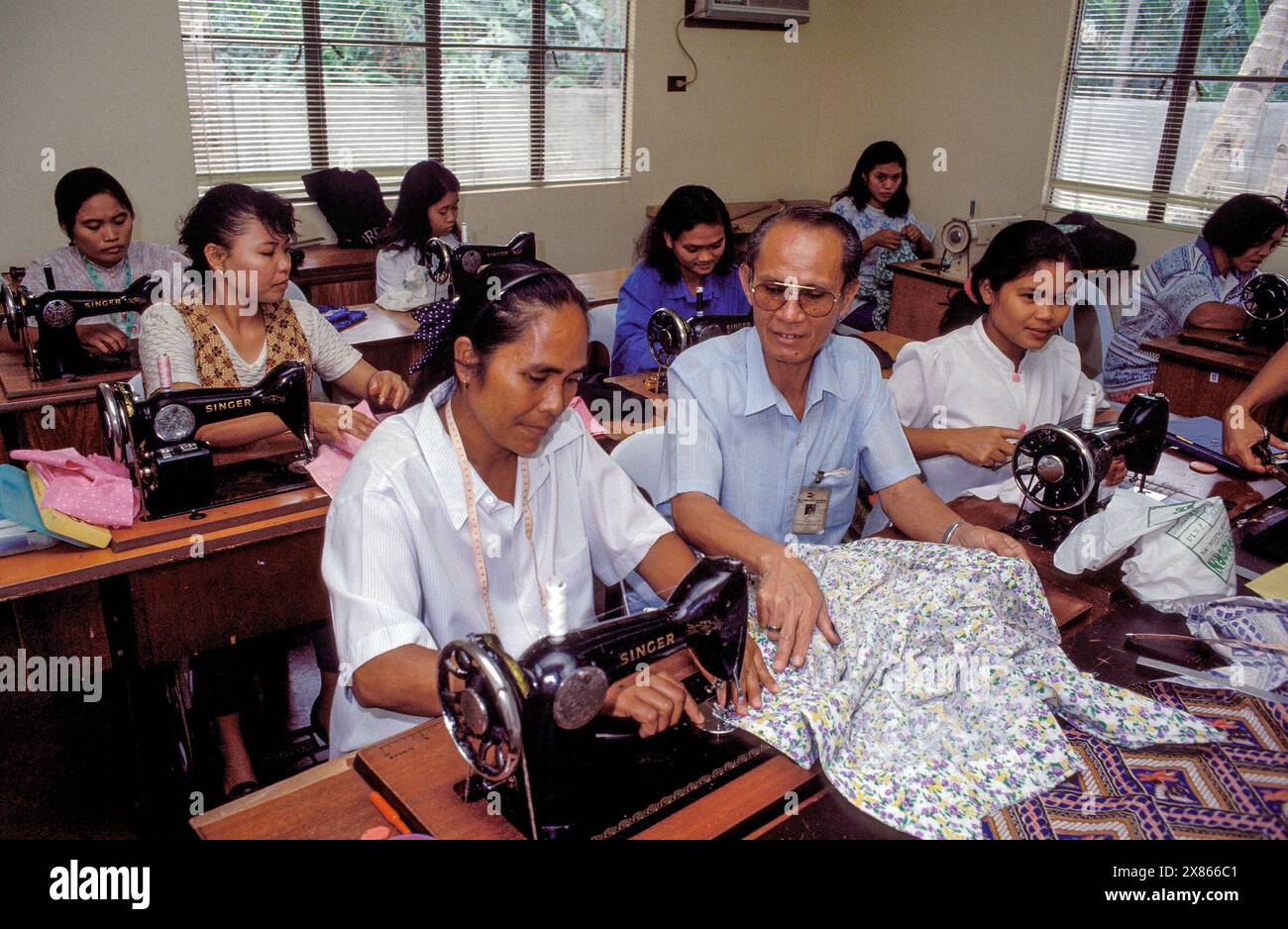 Philippines, Manila, manager instructs woman in a small-scale sewing workshop. Stock Photo