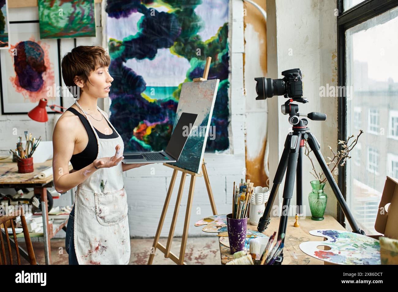 A woman standing in front of an easel with a painting Stock Photo - Alamy