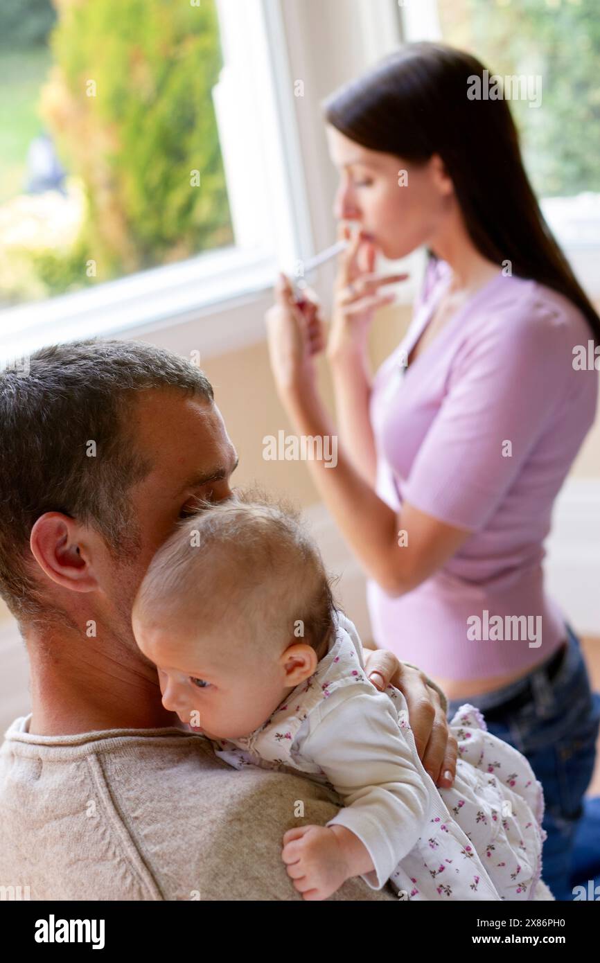 Woman smoking next to newborn baby Stock Photo