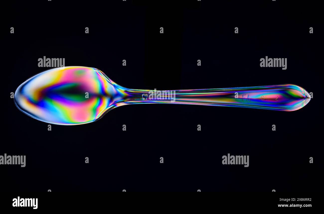 A clear plastic spoon viewed between crossed polarising filters. Stock Photo