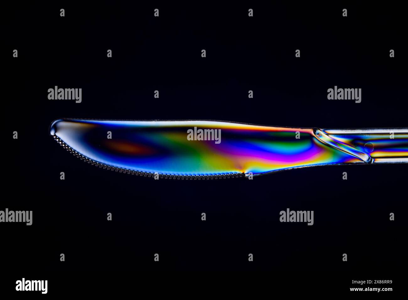 A clear plastic knife viewed between crossed polarising filters. Stock Photo