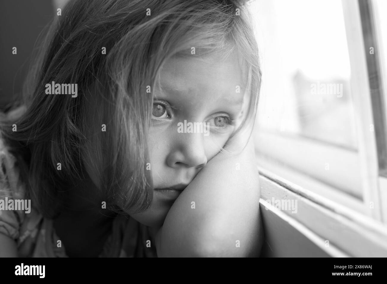 sad little girl looking out the window Stock Photo