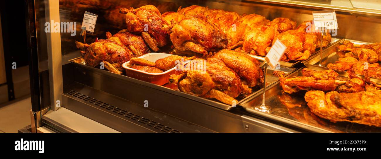 Cremona, Italy - May 5th 2024, Whole roasted chickens on a warm display ...