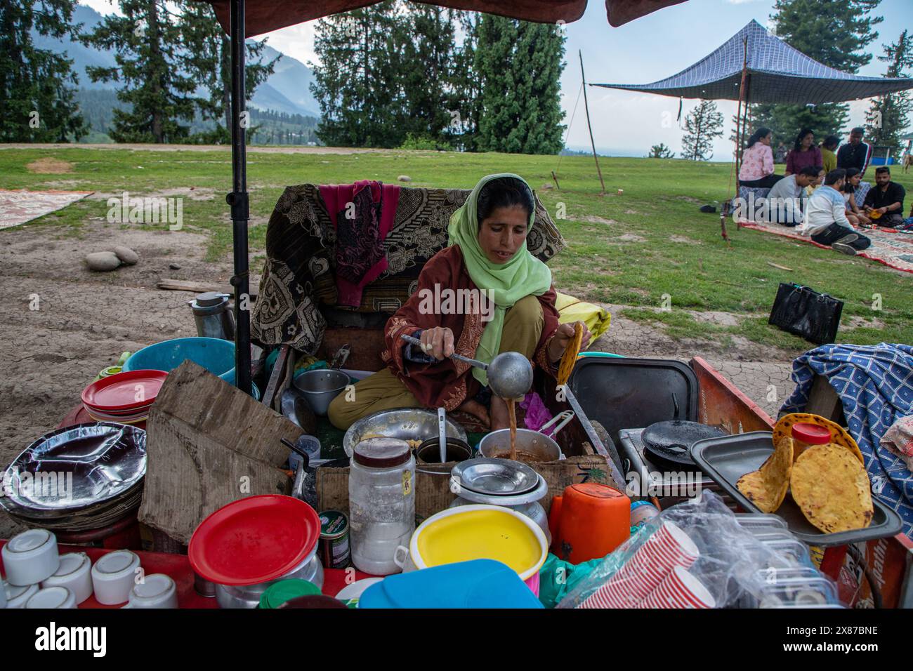 May 23, 2024, Doodhpathri, Jammu And Kashmir, India: A Kashmir woman prepares Noon Chai (salted tea) and serves it with maize flour tortillas to the tourists and locals passing by her roadside stall along the Doodhpathri road in Budgam district, south-west of Srinagar. The authorities have asked the owners of tea vendors to vacate the space they have occupied ''illegally'' within ten days or face action. The officials told a local news agency that the tourism development authority has received multiple complaints that the tea stall owners have been cutting tree branches, thereby harming the pi Stock Photo